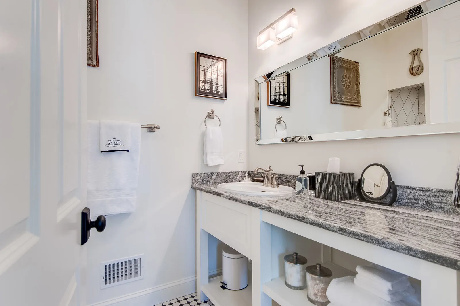 Bathroom with a white open-shelf vanity topped in dark grey Cambria Roxwell quartz