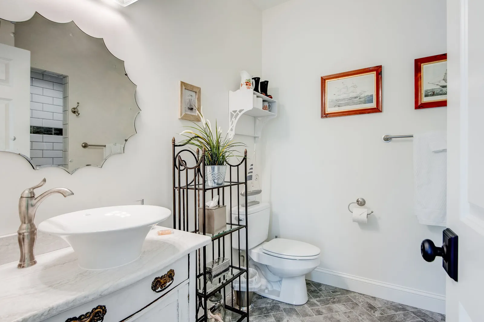 Bathroom with a white vessel sink on a quartz-topped vanity and a scalloped mirror