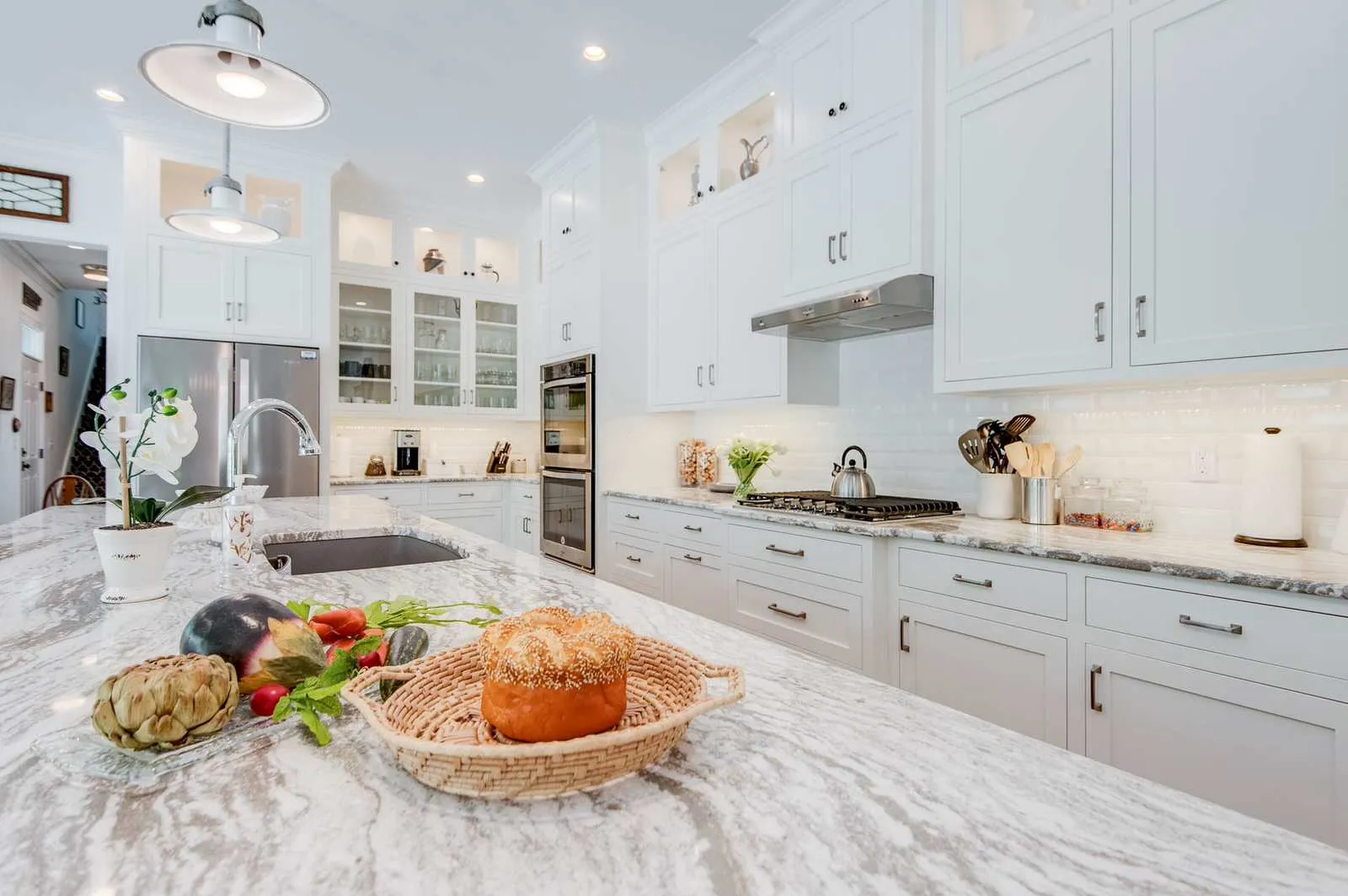 Close view across the Oakmoor island to the sink, white cabinets and glass-front uppers