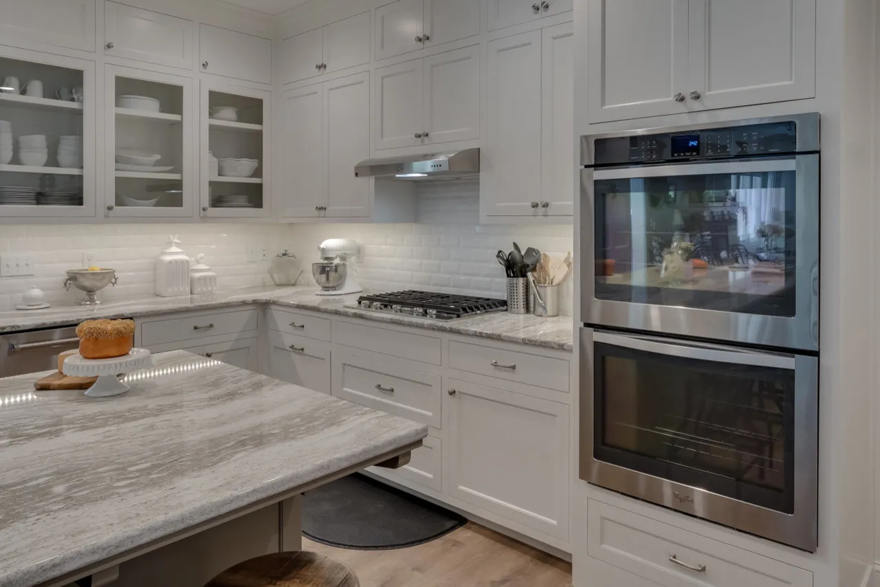 Corner of the kitchen with quartz counters, gas cooktop and stainless double wall ovens